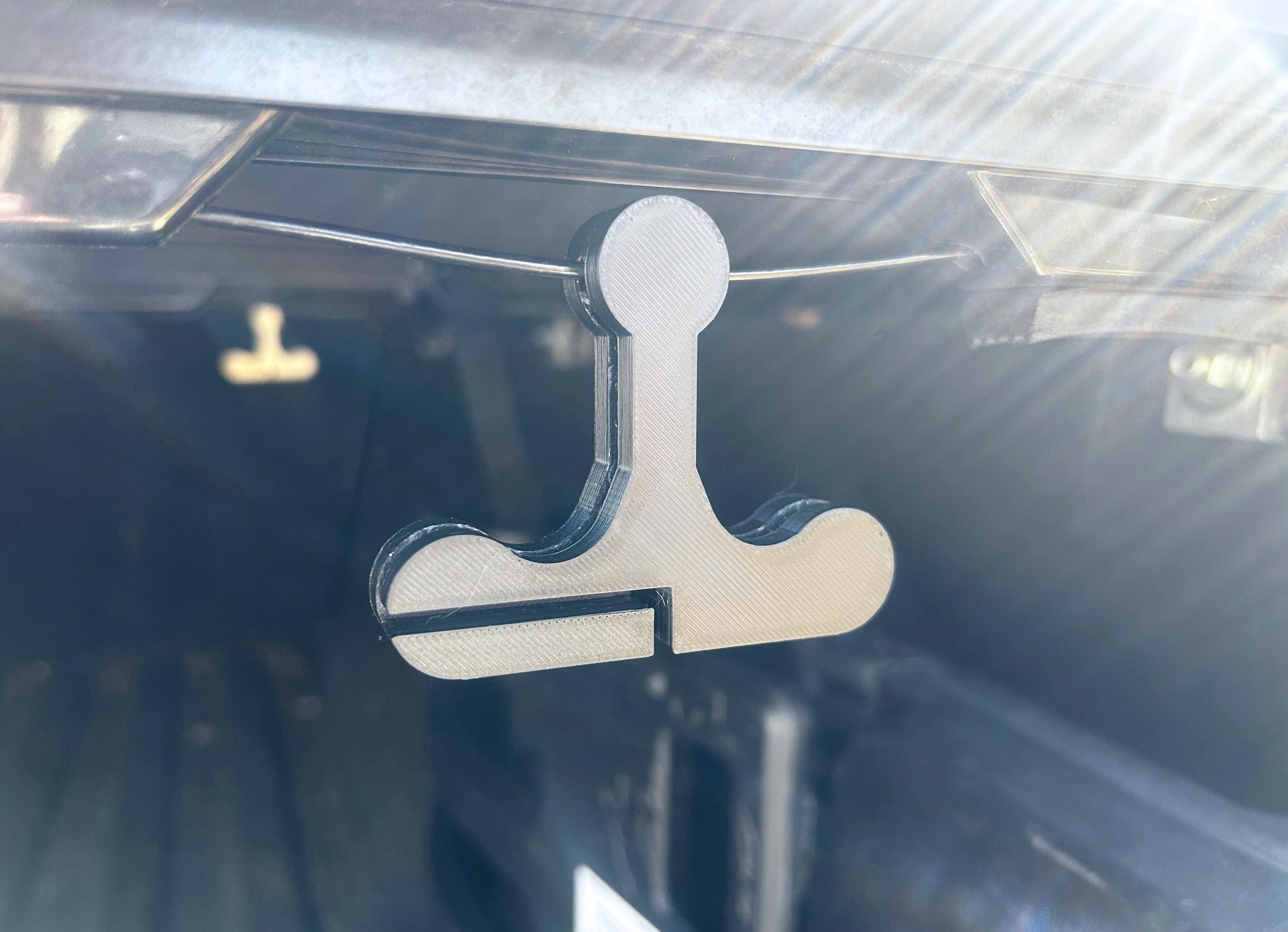 A black handle hanging on the pull cord of a pickup truck bed cover. Designed to found located and pulled easier.