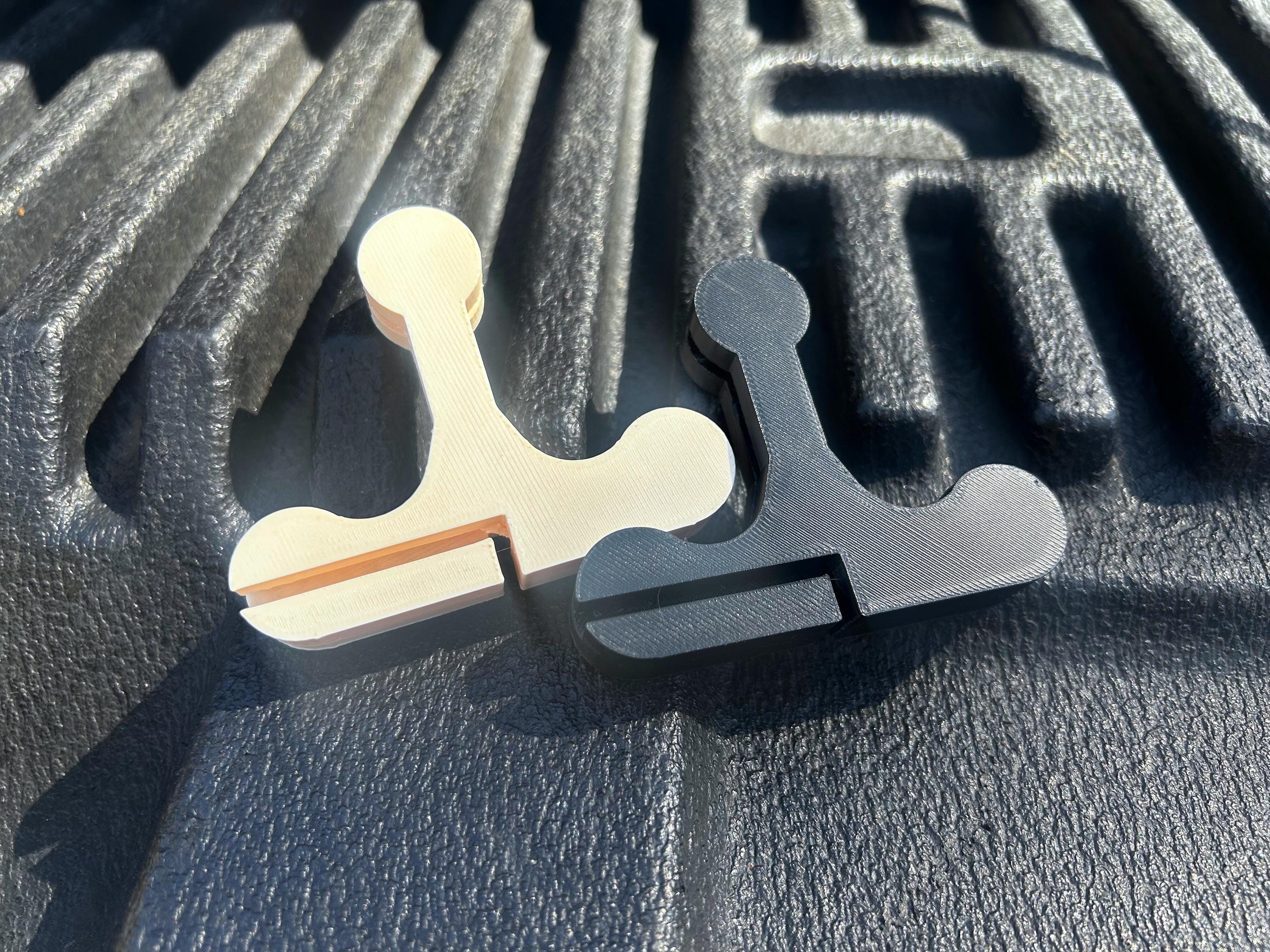 Two bed cover handles, one black, and one beige, sitting on a truck tailgate.