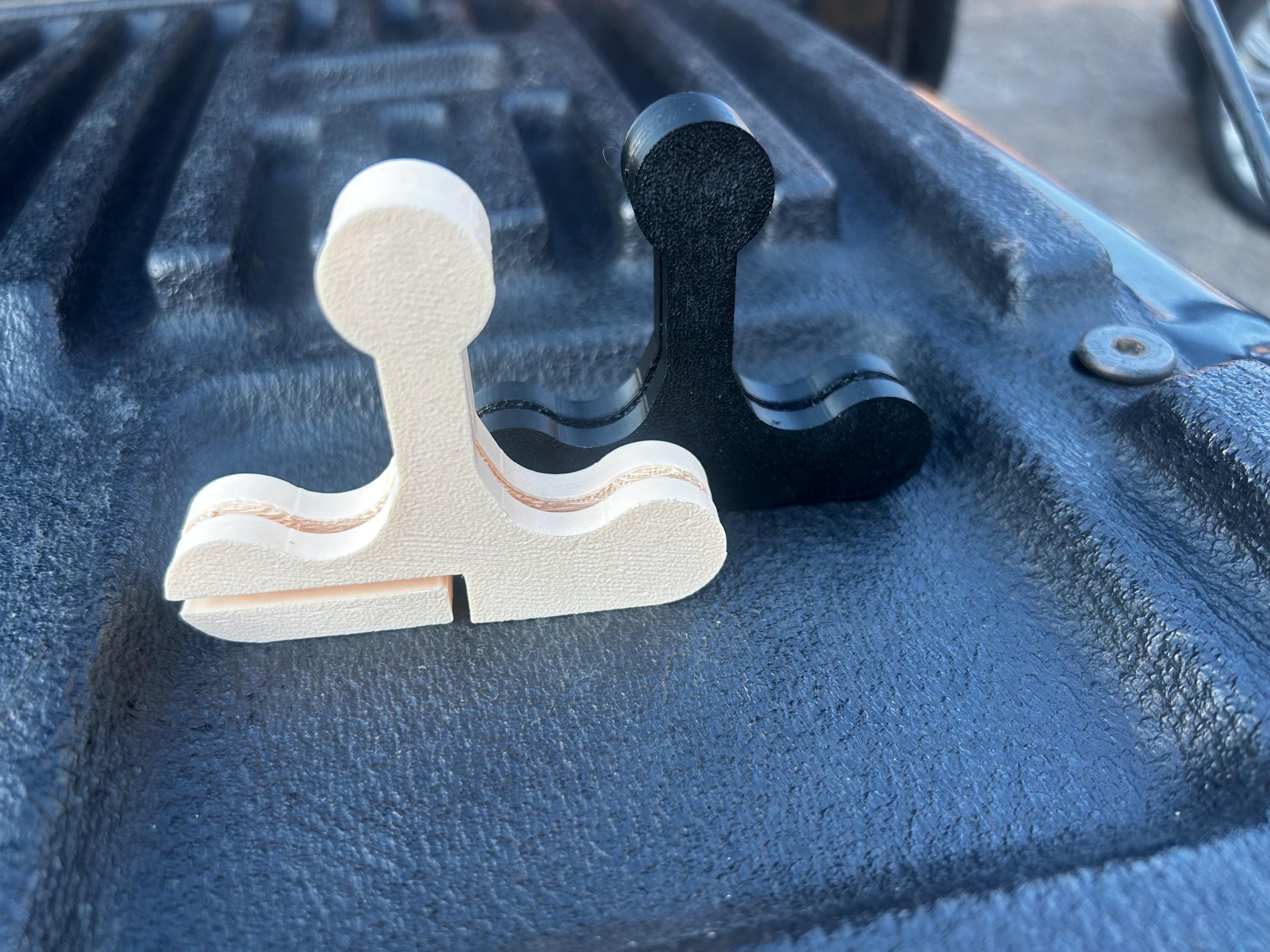 Two bed cover handles, one black, and one beige, sitting on a truck tailgate.